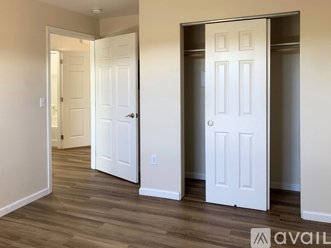 A room with two white doors and wooden flooring.