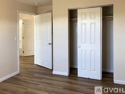 A room with two white doors and wooden flooring.