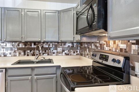 A kitchen with a black microwave above a stove top oven.