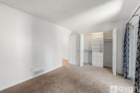 A bedroom with a carpeted floor and white walls.