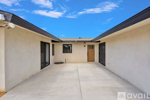 A sunny day with a clear blue sky, a white building with a brown door and windows.