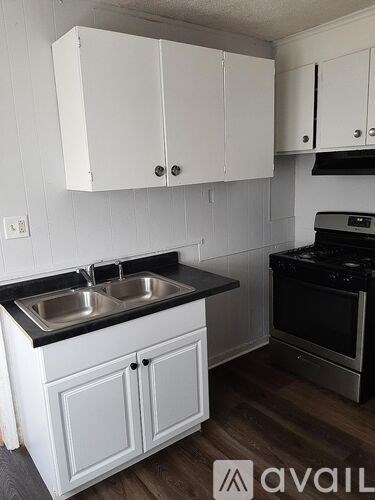 A kitchen with white cabinets and a black countertop.