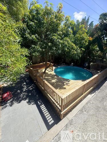 A small wooden deck with a round blue pool in the middle.