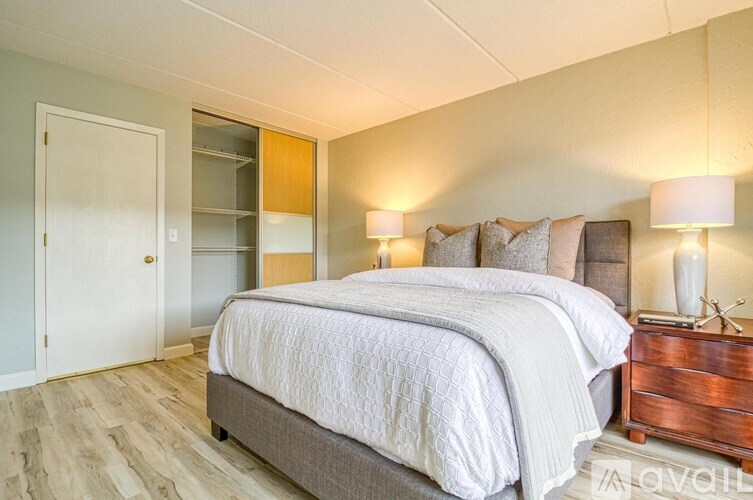 A bedroom with a large bed and a wooden nightstand.