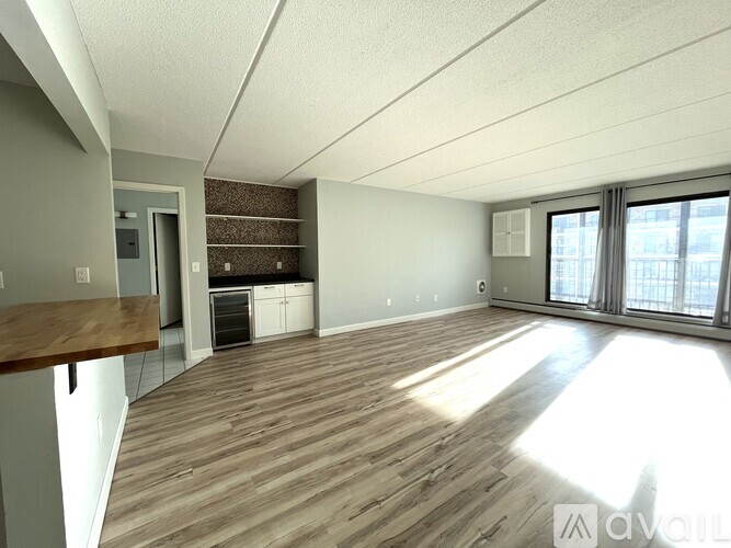 A spacious room with wooden flooring and a large window.