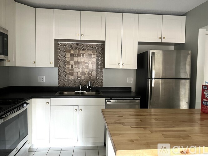A kitchen with white cabinets and a wooden counter top.