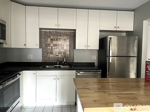 A kitchen with white cabinets and a wooden counter top.