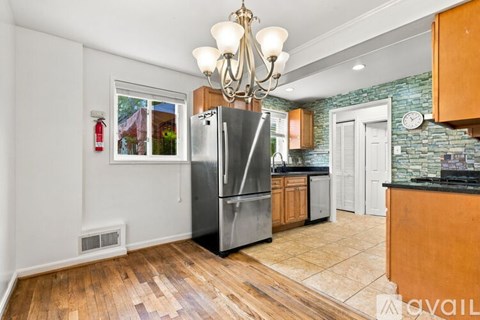 A kitchen with a stainless steel refrigerator and wooden floors.