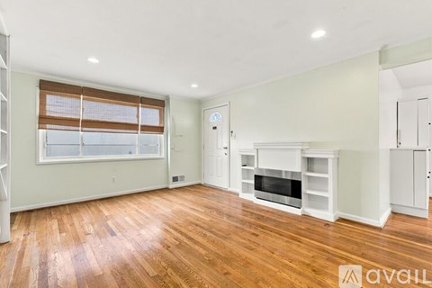 A spacious living room with wood flooring and a fireplace.