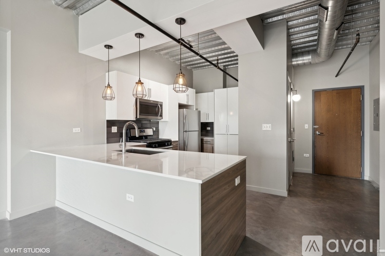 A modern kitchen with a white countertop and pendant lights.