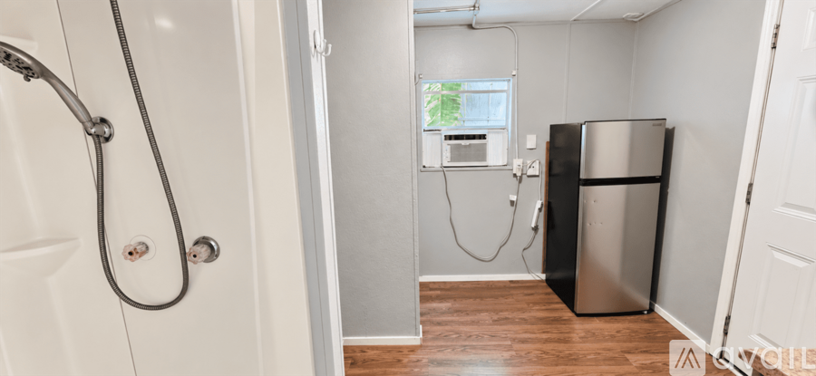 A small bathroom with a shower and a refrigerator.