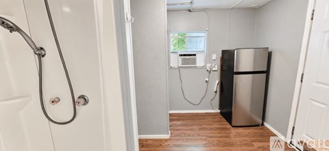 A small bathroom with a shower and a refrigerator.