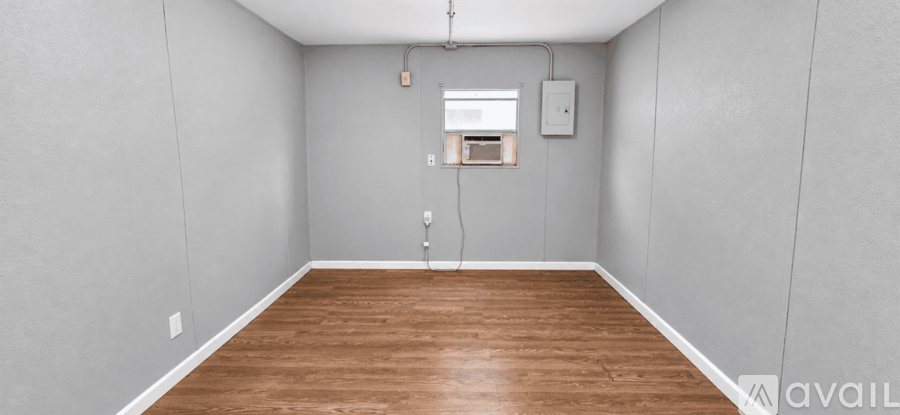 A room with wooden flooring and a window with a white frame.