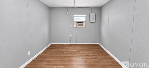 A room with wooden flooring and a window with a white frame.