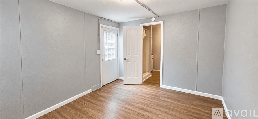 A room with wooden flooring and a white door.