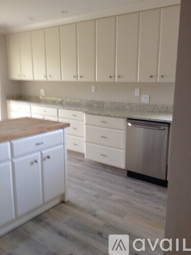 A kitchen with white cabinets and a wooden counter top.