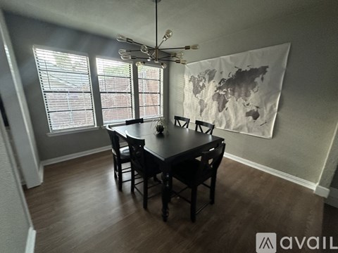 A dining room with a table and chairs and a world map on the wall.