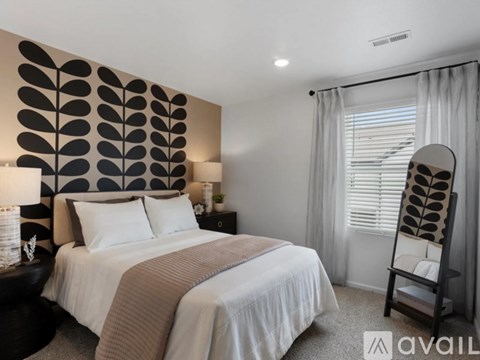 A bedroom with a large bed and a leaf patterned wall.