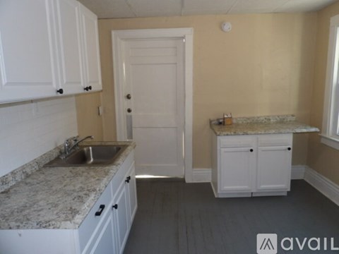 A kitchen with white cabinets and a granite countertop.