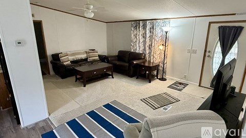A living room with a brown couch and a blue rug.