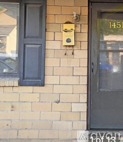 A beehive is attached to a wall above a black door.