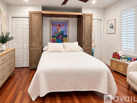 A bedroom with a large bed and a painting on the wall.