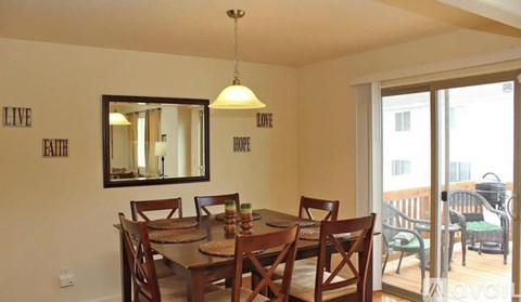 A dining room with a wooden table and chairs, a mirror, and a wall with the words "LIVE FAITH HOPE" written on it.