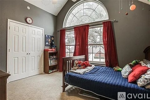 A bedroom with a bed, a window with red curtains, and a bookshelf.
