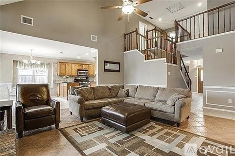 A living room with a brown leather chair and a brown leather ottoman.