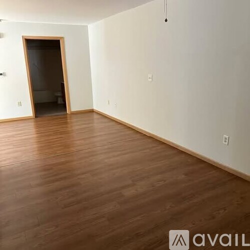 A room with wooden flooring and a doorway leading to another room.