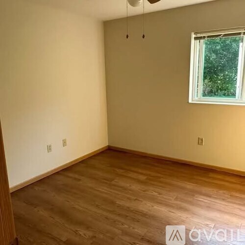A room with wooden flooring and a window.