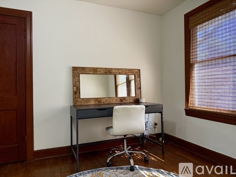 A room with a desk and chair and a mirror on the wall.