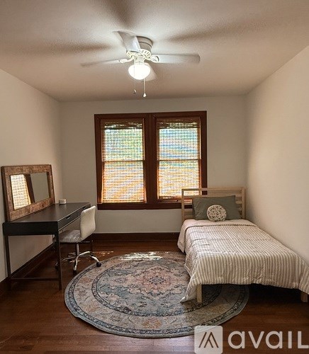 A bedroom with a bed, desk, and window.