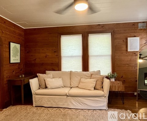 A living room with a white couch and wooden walls.