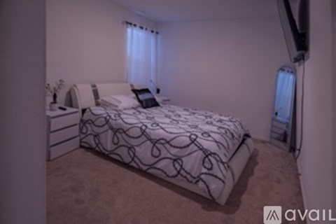 A bedroom with a bed, nightstand, and a window with curtains.