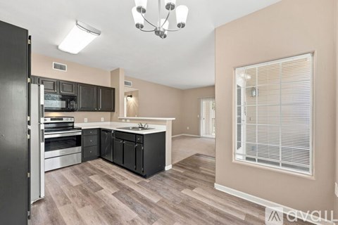 A modern kitchen with a black refrigerator and wooden flooring.