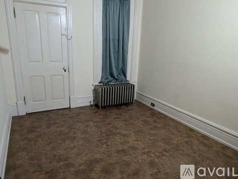 A room with a door, a radiator, and a curtain.