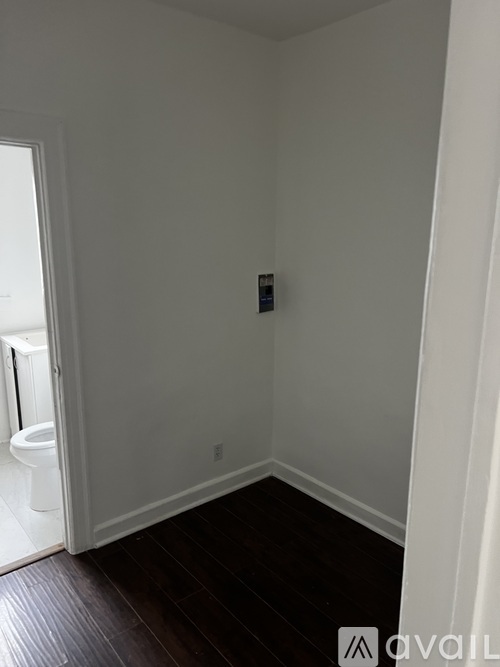A white bathroom with a toilet and a wooden floor.