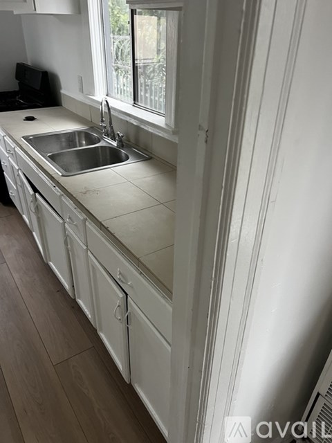 A kitchen with white cabinets and a stainless steel sink.