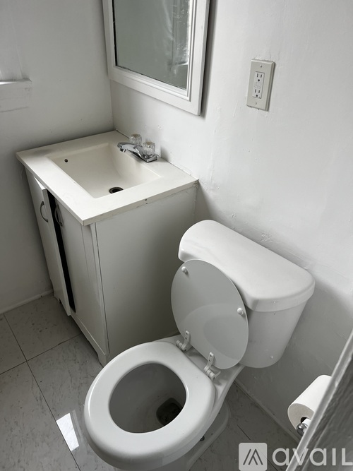 A white toilet with a white sink in a small bathroom.