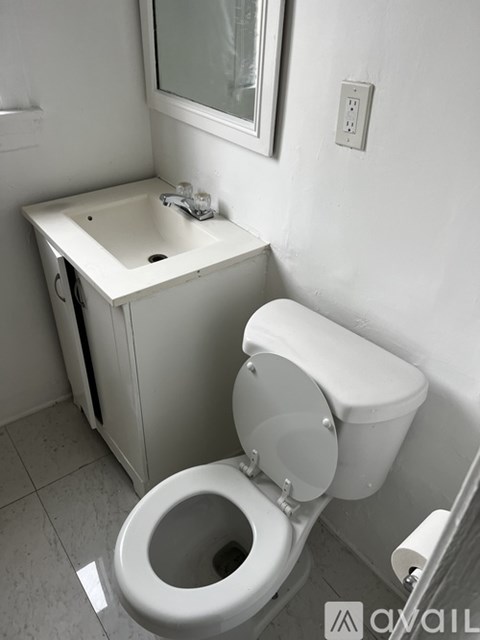 A white toilet with a white sink in a small bathroom.