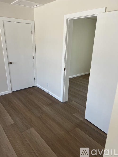 A room with a white door and a white wall with a wooden floor.