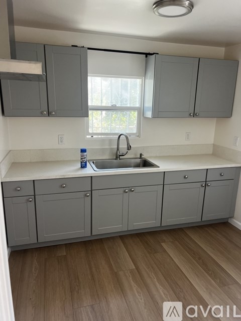 A kitchen with grey cabinets and a wooden floor.