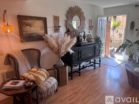 A living room with a wooden floor and a large mirror on the wall.
