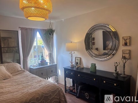 A bedroom with a bed, a dresser, and a mirror on the wall.