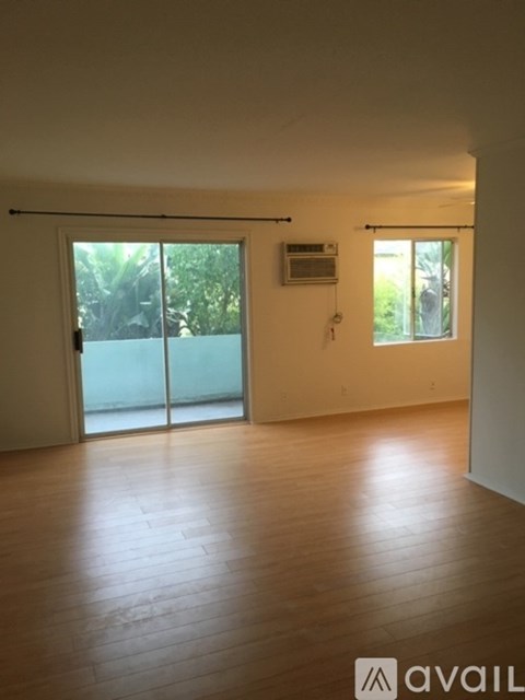 A room with wooden flooring and a sliding glass door leading outside.