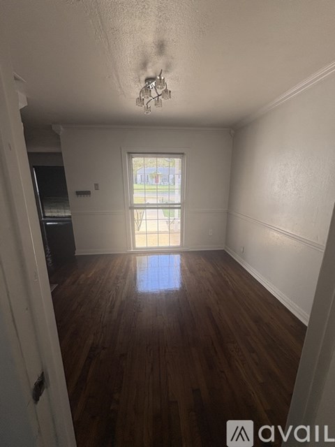 A room with wooden floors and a window showing a view of a building outside.