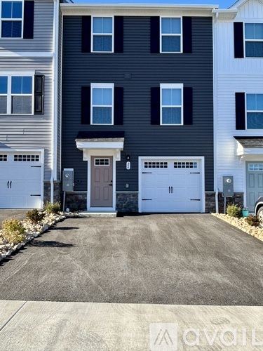 A two-story house with a garage door and a driveway.