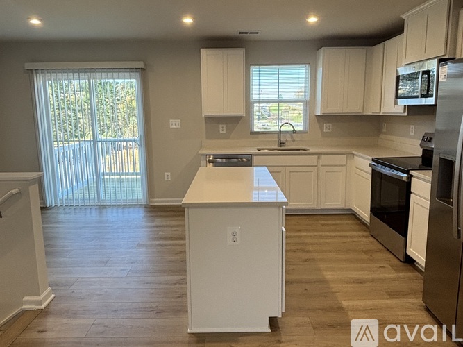 A kitchen with white cabinets and a wooden floor.