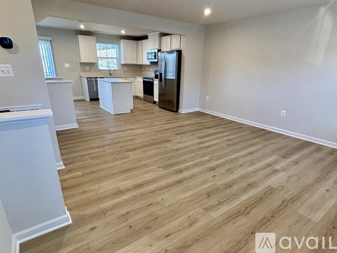 A spacious kitchen with wooden flooring and white cabinets.
